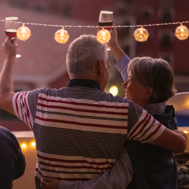 Pareja de jubilados felices con las copas en alto y abrazados