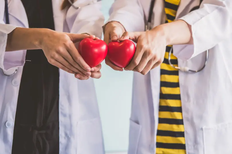 dos doctores sujetando un corazón rojo para el cuidado de la salud