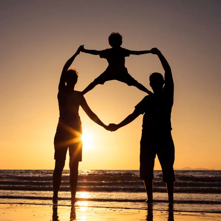 Silueta de familia feliz que juega en la playa ilustrando el seguro de vida